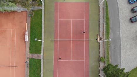 Aerial-shot-of-2-vs-2-Tennis-on-Clay-Court,-Outdoor-Recreational-Sports-Facility