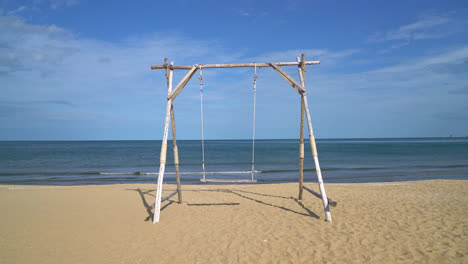 wooden-swing-on-the-beach-with-sea-beach-background