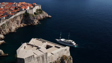 Boat-With-Tourists-Cruising-At-Adriatic-Sea-Near-Walls-of-Dubrovnik-And-Lovrijenac-In-Croatia