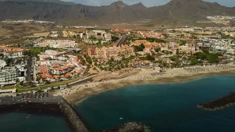 Impresionante-Vista-Panorámica-De-La-Ciudad-España-Tenerife-En-La-Costa-Del-Mar-De-Agua-Azul-Con-Rocas-De-Playa-Y-Montañas-En-El-Fondo