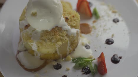 Close-up-shot-of-sweet-apple-crumble-dessert-with-ice-cream-on-plate---4K-footage