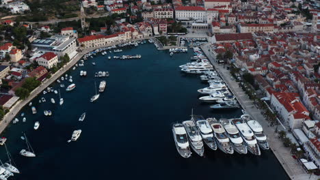 Luxury-Yachts-And-Boats-Dock-At-Marina-With-Waterfront-Buildings-At-Sunrise-In-Hvar,-Croatia