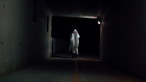 A-person-putting-on-a-white-sheet-over-their-head-and-puts-on-sunglasses-to-look-like-a-cool-ghost-costume-for-Halloween-in-a-small-tunnel-at-night-in-Provo,-Utah-on-a-cold-autumn-night