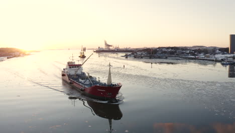 Drone-circulating-a-large-fishing-boat-near-the-harbor-of-Gothenburg,-Sweden-during-sunset-in-the-cold-winter-time