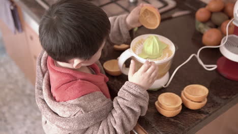 Asian-boy-learning-how-to-squeeze-oranges-to-make-juice-by-himself