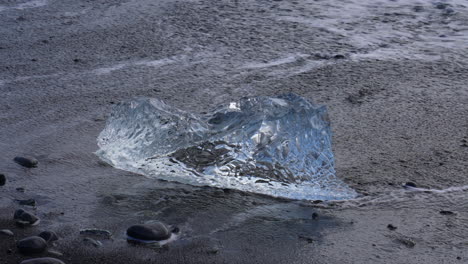 Close-up-shot-of-iceberg-on-ocean-shore-overflowing-by-water-of-ocean-in-Iceland