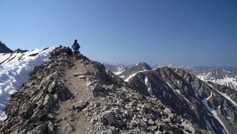 Alpinista-Femenina-En-La-Cima-De-La-Cordillera-Con-Nieve-En-Las-Laderas