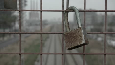 Old-rusty-love-lock-hanging-on-the-iron-fence-of-a-train-bridge