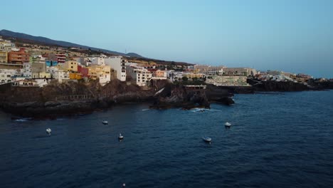 Increíble-Disparo-De-Drone-En-4k-En-Tenerife-En-España-Los-Gigantes-En-La-Costa-Junto-Al-Mar-Con-Barcos-Y-Montañas-En-El-Fondo-Edificios-De-La-Ciudad-Hoteles-Mar-Laguna-De-Agua-Azul