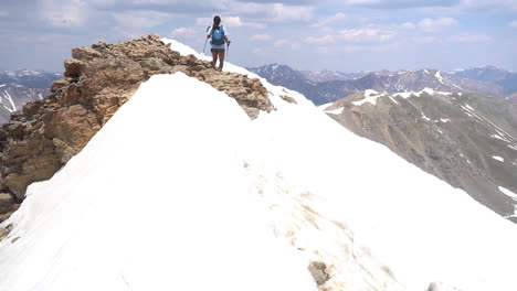 Mujer-Montañera-Con-Bastones-De-Trekking-En-La-Cumbre-Nevada-Con-Una-Vista-Increíble-De-La-Cordillera
