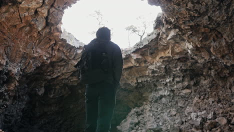 Hiker-admires-large-skylight-in-cave-roof-at-El-Malpais-National-Monument