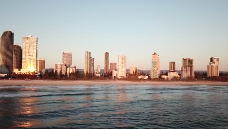 Drone-aerial-over-Broadbeach-city-with-waves-on-the-beach-during-sunrise