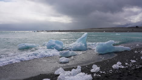 Waves-Crashing-On-Icebergs-On-Shoreline-Of-Black-Beach-In-Iceland