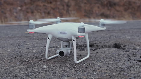 Quadcopter-Drone-Girando-Hélices-Y-Despegando-En-Carretera,-Cámara-Lenta