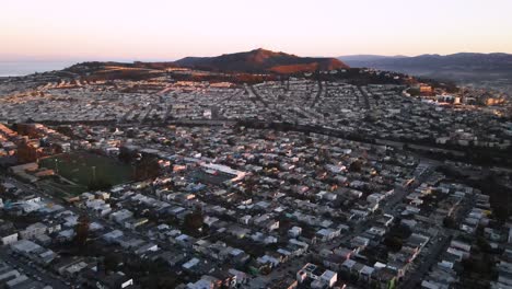 Daly-City-Beherbergt-Luftdrohnenansicht-Mit-San-Bruno-Berg-Im-Hintergrund-Während-Des-Sonnenuntergangs,-Gradientenhimmel