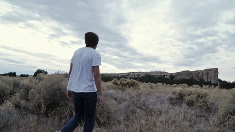 Young-man-wearing-beanie-walking-through-desert-landscape,-slow-motion