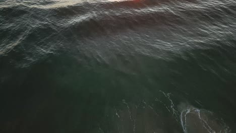 Drone-aerial-over-waves-during-sunrise-at-beach