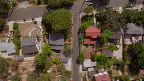 Overhead-aerial-view-of-houses-and-street-in-Eagle-Rock-neighborhood-in-Los-Angeles,-California-with-scrolling-up-to-reveal-a-car-pulling-into-a-parking-spot-in-a-parking-lot