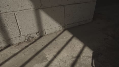 Moving-gate-shadows-on-concrete-wall-and-floor-sunny-afternoon-jail-atmosphere