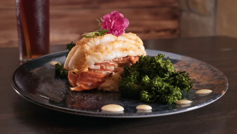 Broiled-Maine-lobster-tail-garnished-with-roasted-broccolini-and-orzo-on-a-black-stoneware-plate,-slider-HD