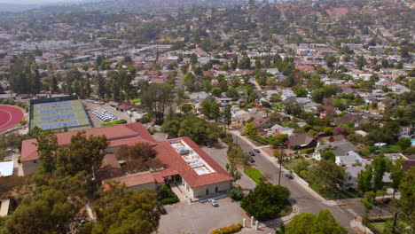 Flyover-Eagle-Rock-neighborhood-in-Los-Angeles,-California-on-a-sunny-summer-day-with-houses,-streets,-and-Occidental-college-campus-tennis-courts