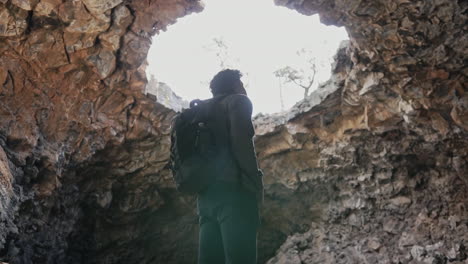 Man-looking-up-at-massive-cave-opening-at-El-Malpais-National-Monument-NM