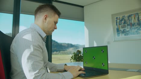 Caucasian-man-works-on-his-laptop-at-a-desk-in-his-office,-greenscreen