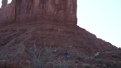 Hiker-stops-to-look-at-The-Mitten-in-Monument-Valley-Arizona,-slow-motion