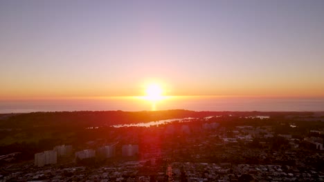 Sunset-Over-the-Ocean-and-residential-houses-in-foreground-drone-Pan-right-across-the-horizon