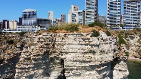 Modern-Buildings-On-The-Mediterranean-Coast-In-Beirut,-Lebanon,-View-From-Area-Next-To-Famous-Raouche-Rocks---aerial-pullback