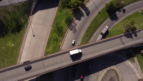 Aerial-top-down-of-truck-leaving-highway,-passing-under-bridge-on-giant-intersection-in-Buenos-Aires