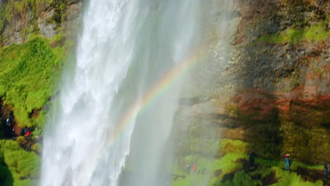 Starke-Wasserströmung,-Die-Vom-Seljalandsfoss-Wasserfall-Mit-Blick-Auf-Einen-Regenbogen-In-Island-Fällt