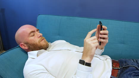Close-shot-of-man-Lying-On-Sofa-And-Using-Mobile-Phone