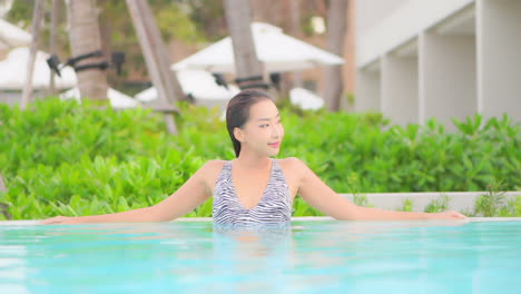 Schöne-Junge-Asiatin-Entspannen-Und-Lächeln-Im-Schwimmbad-Des-Resorts-Für-Den-Urlaub