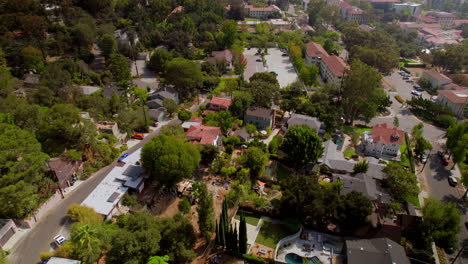 Flyover-houses-and-street-in-Eagle-Rock-neighborhood-of-Los-Angeles-towards-Occidental-college-campus-and-parking-lot-with-a-blue-car-driving-down-the-street