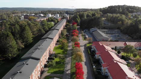 Luftaufnahme-Einer-Terrassenförmig-Angelegten-Reihe-Nachhaltiger-Häuser,-Die-Von-Roten-Und-Grünen-Bäumen-Gesäumt-Sind