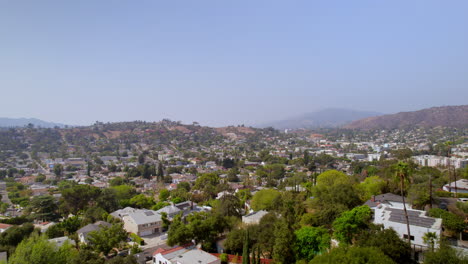Wide-aerial-view-of-Eagle-Rock-neighborhood-in-Los-Angeles,-California-with-a-slow-pull-back-over-houses-on-a-beautiful-summer-day