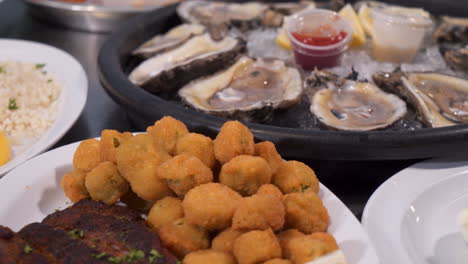 A-variety-of-seafood-platters,-blackened-fish-and-okra,-a-dozen-raw-oysters-on-the-half-shell,-close-up-slider-4K