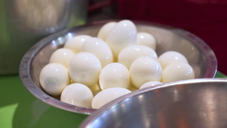Cook-places-freshly-peeled-hard-boiled-eggs-into-full-bowl,-slow-motion-HD
