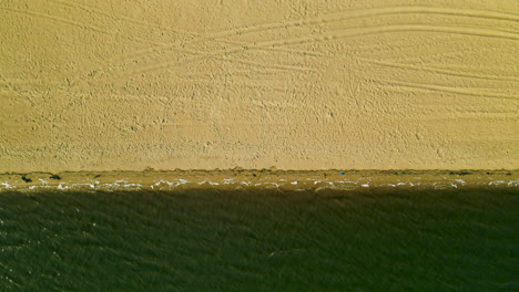 Luftaufnahme-Von-Oben-Aus-Der-Höhe-Der-Wellen-Des-Flusses-Piedras,-Die-über-Die-Küste-Des-Sandstrandes-Rollen,-Wenn-Nur-Wenige-Und-Nicht-Erkennbare-Menschen-Am-Wasser-Stehen