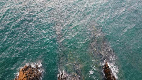 Top-aerial-drone-view-of-ocean-waves-crash-against-rocks-in-Brittany,-France-Bretagne