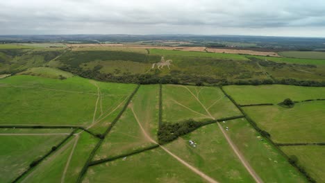 Osmington-White-Horse-limestone-figure-art-on-hillside-slope-aerial-view-reversing-across-agricultural-field
