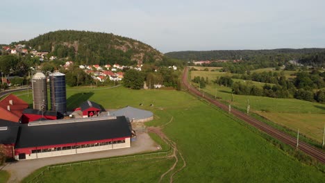 SJ-X40-Double-Decker-Electric-Train-Passing-a-Farm-in-Sweden,-Aerial-View