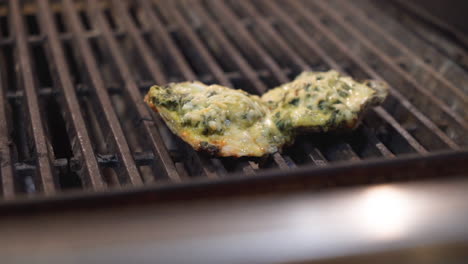Grilled-Oysters-Rockefeller,-cheese-and-butter-sauce-melt-and-bubble-over-grill-flames,-slow-motion-close-up-HD