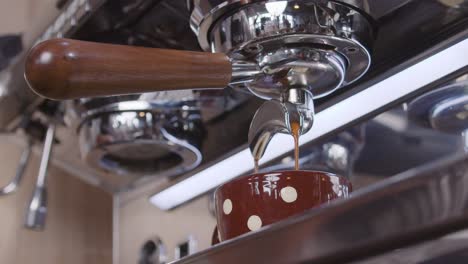 Idyllic-slow-motion-close-up-of-an-industrial-coffee-maker-pouring-fresh-coffee-in-a-cup-to-keep-up-with-the-routine