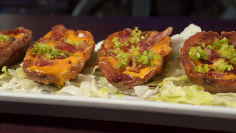 Loaded-potato-skins-on-a-lettuce-lined-tray,-slider-close-up-HD