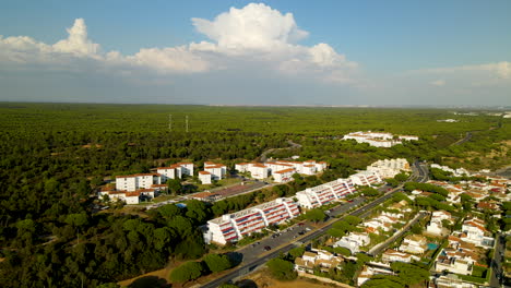 Aerial-shot-of-El-Rompido-City-with-apartment-blocks-in-front-of-green-woodland-in-Spain