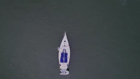 Birdseye-view-of-white-sailboat-anchored-in-the-water,-United-States