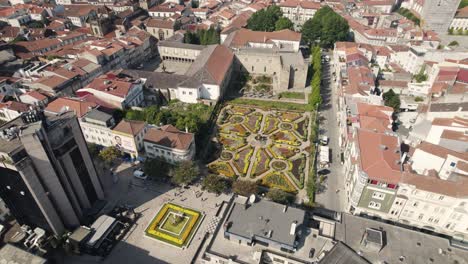 Aerial-circular-view-of-Braga-city-center,-with-people-walking-by-and-flowerbeds