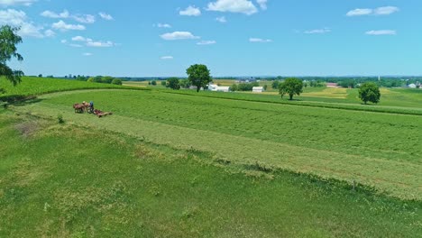 Eine-Luftaufnahme-Eines-Amish-Bauern-Mit-Drei-Pferden,-Die-An-Einem-Schönen-Tag-über-Die-Landschaft-Ernten